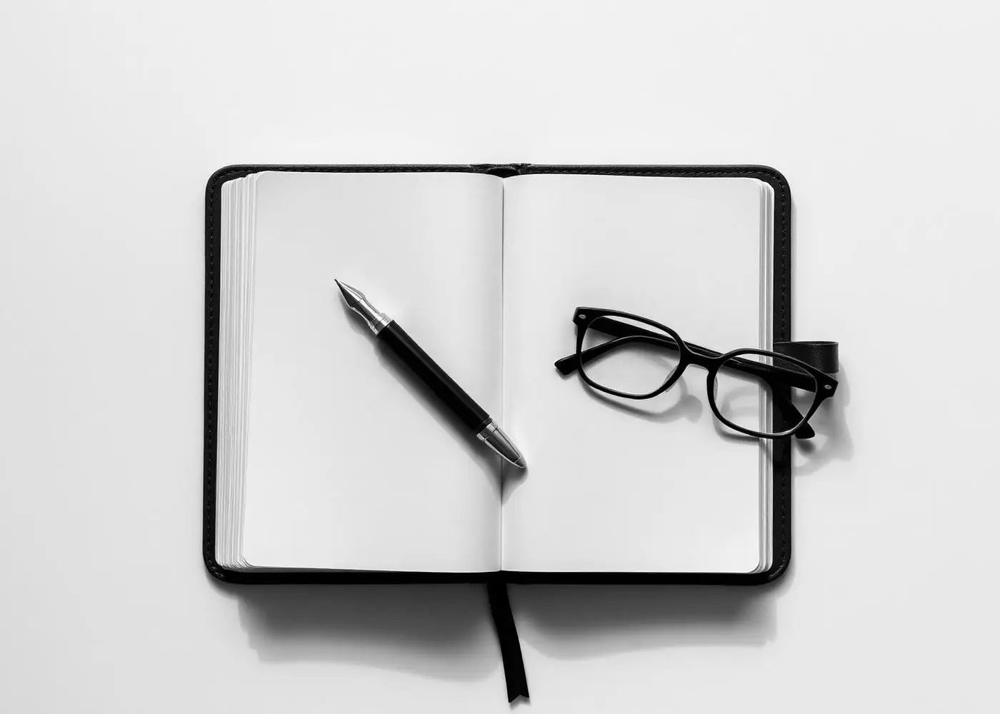 Open leather ledger with fountain pen and reading glasses